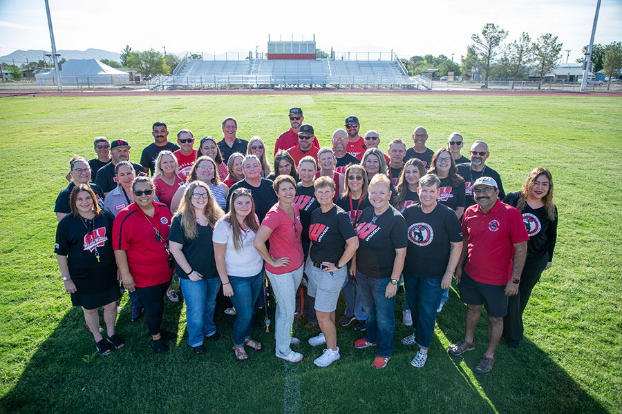 Group of happy staff members posing for a photo outside on campus